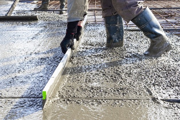 Technician repairing lifted section of concrete pathway