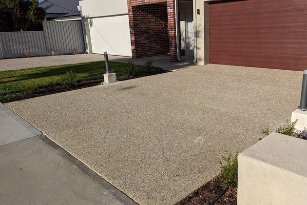 Curved exposed aggregate driveway forming a circular pattern in front of a house