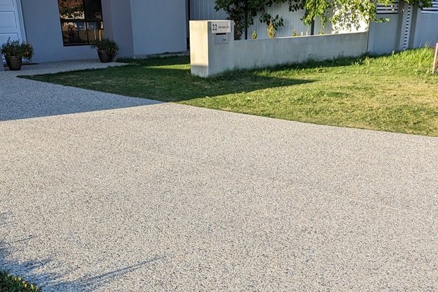 Sleek exposed aggregate concrete driveway leading to a contemporary home in Chelsea